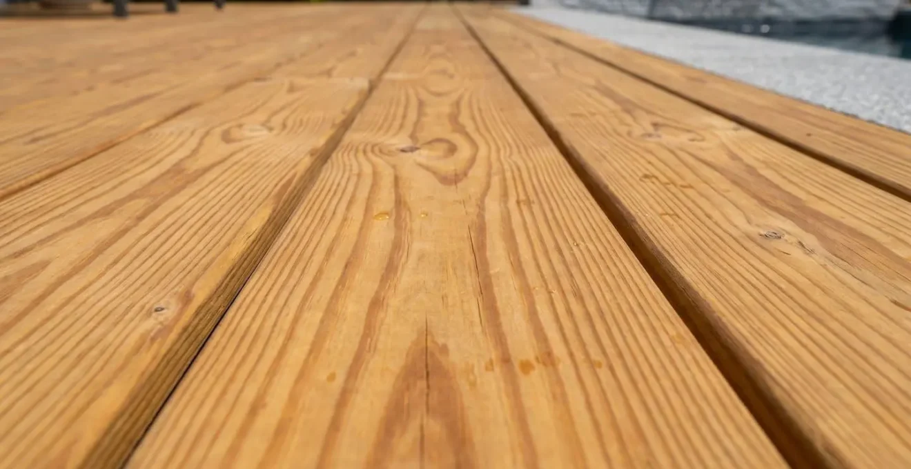 Gros plan sur les lames de bois d'une piscine, montrant le grain naturel et la texture miel caractéristique du pin autoclave